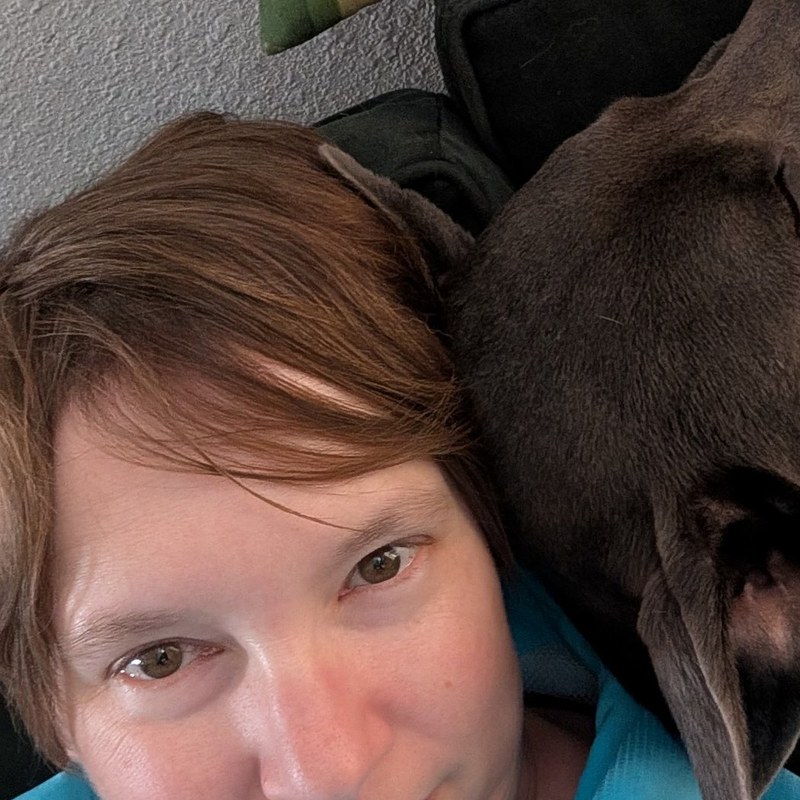 Amanda Lundberg, White Coat captioner, resting with her grey rescue dog