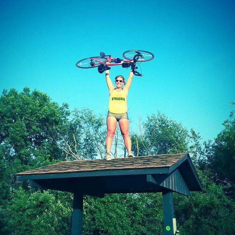 Diane Scott, White Coat captioner, holding her bicycle overhead after a ride