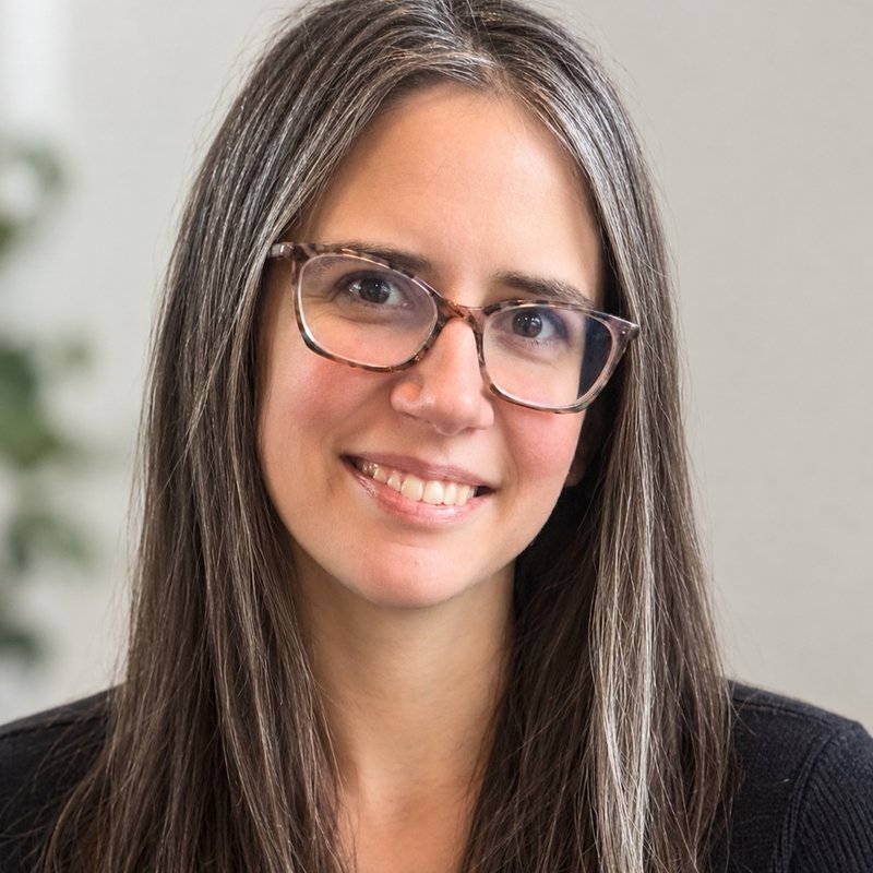 Maggie Rumfelt, White Coat captioner, smiling in tortoiseshell glasses